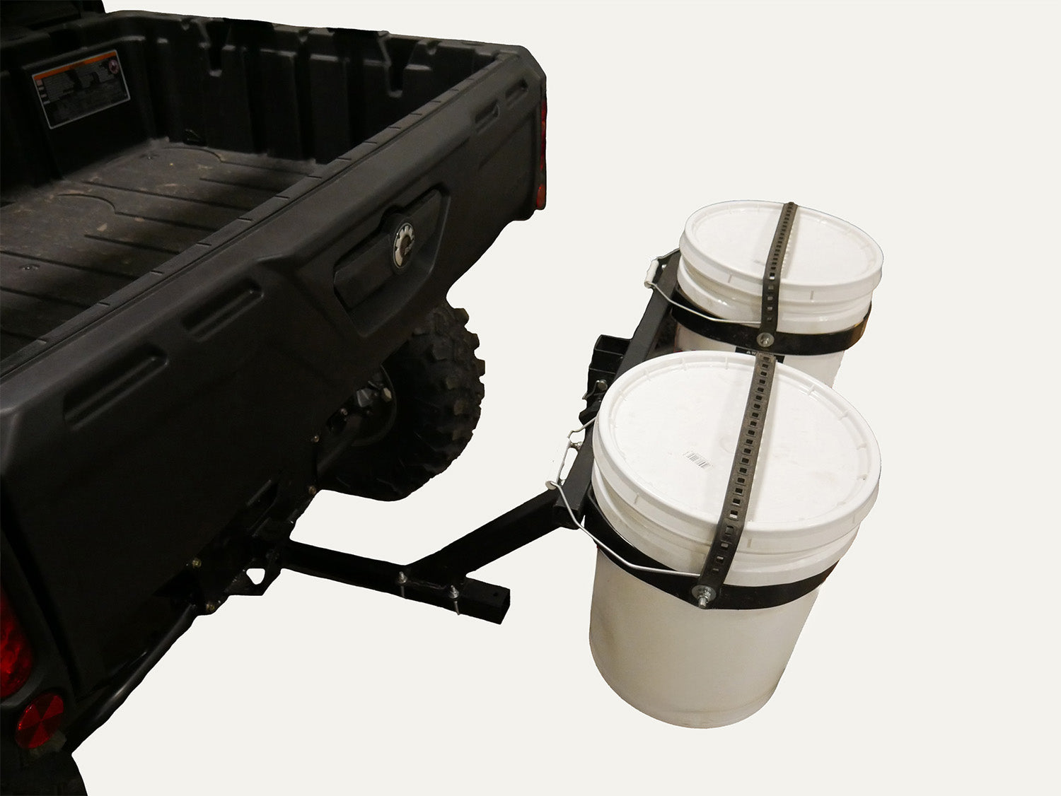Two white buckets attached to a black hitch receiver on a vehicle.